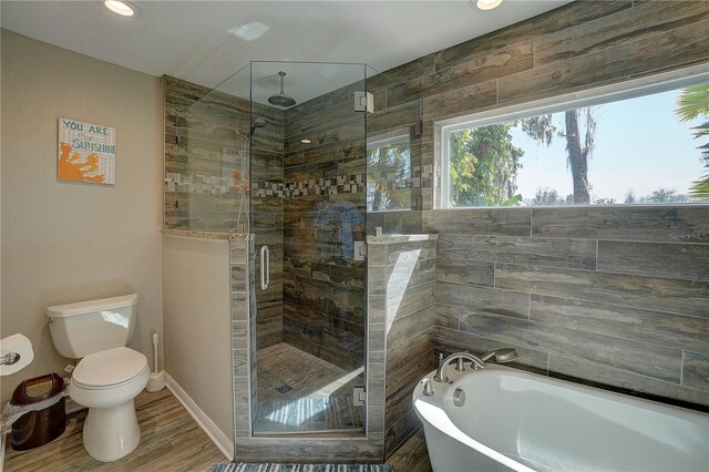 full bathroom with a washtub, toilet, a shower stall, wood finished floors, and baseboards