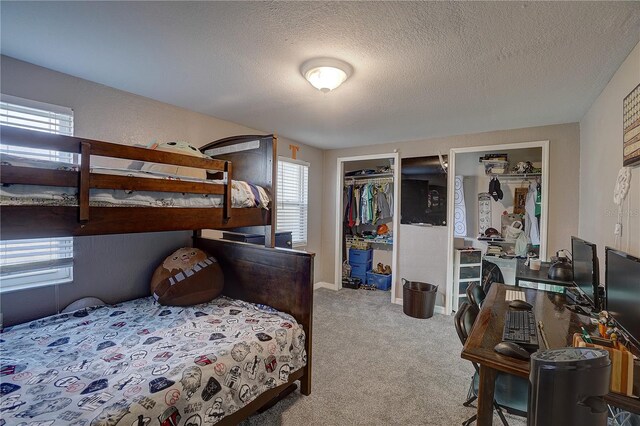 carpeted bedroom with multiple closets, a textured ceiling, and baseboards
