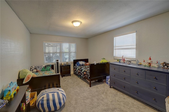 bedroom with light carpet, multiple windows, and a textured ceiling
