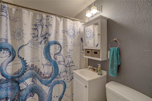 bathroom featuring a shower with shower curtain, a textured wall, vanity, and toilet