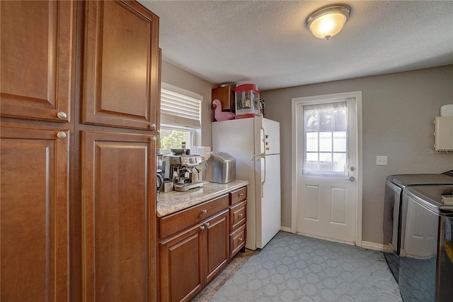 kitchen with brown cabinetry, freestanding refrigerator, a textured ceiling, and baseboards