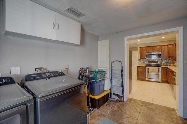 laundry room with visible vents, cabinet space, light tile patterned flooring, a textured ceiling, and separate washer and dryer