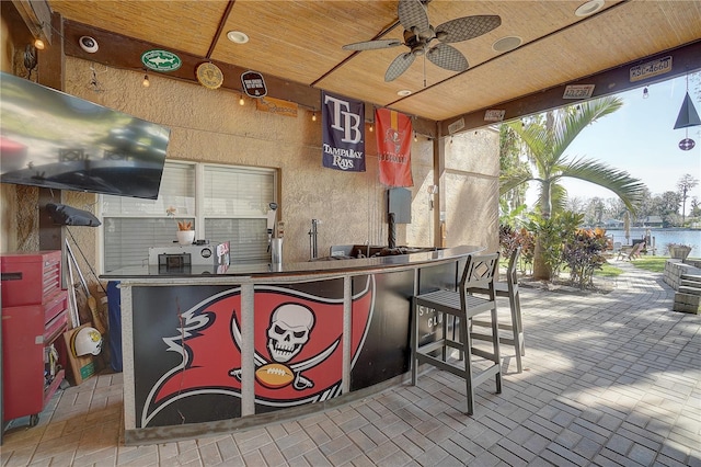 view of patio with a water view, outdoor wet bar, and a ceiling fan