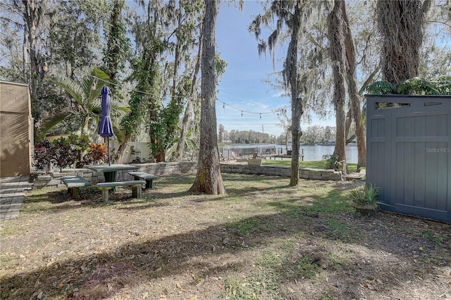 view of yard with an outbuilding, a shed, a water view, and fence