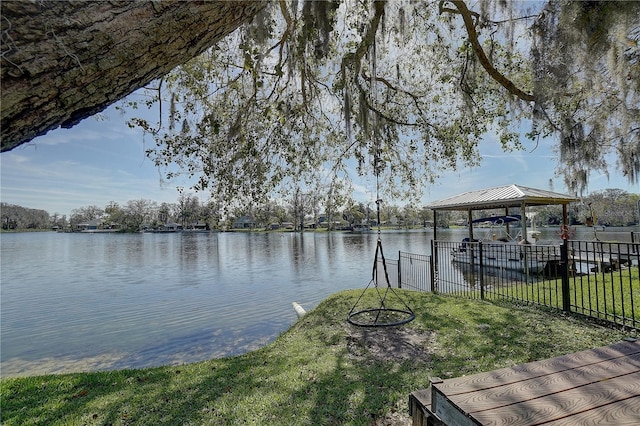 view of dock with a gazebo, a lawn, a water view, and fence