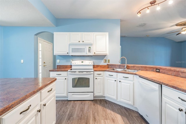 kitchen with arched walkways, white appliances, a sink, and white cabinetry