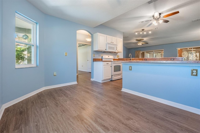 kitchen with white appliances, arched walkways, white cabinets, a peninsula, and light countertops