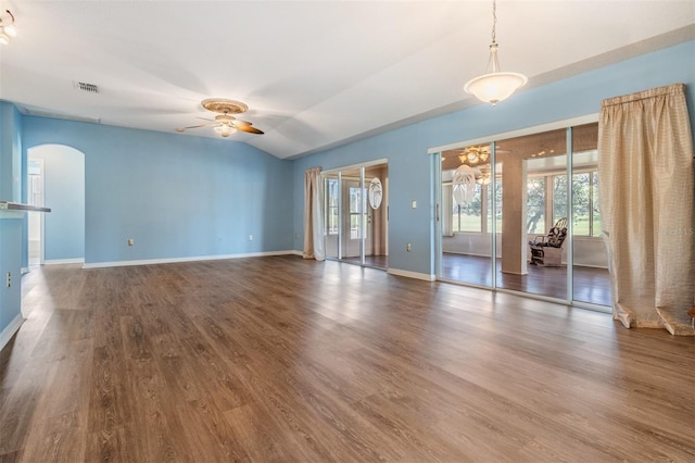 unfurnished living room with ceiling fan, arched walkways, dark wood-type flooring, visible vents, and baseboards