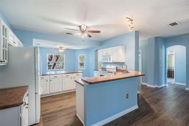 kitchen featuring a peninsula, white appliances, glass insert cabinets, and white cabinetry