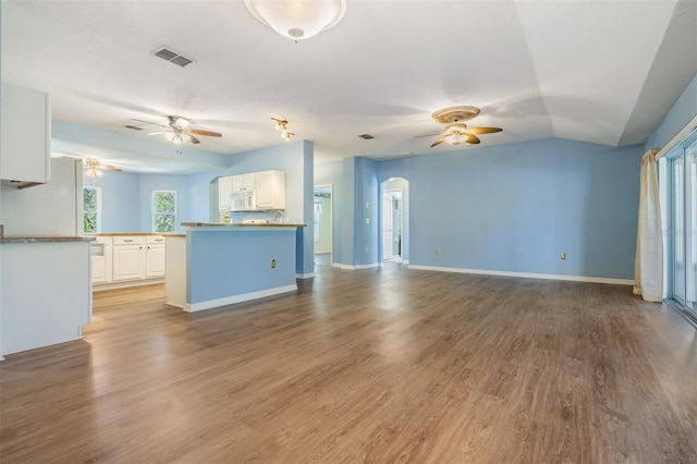 unfurnished living room with light wood finished floors, ceiling fan, visible vents, and arched walkways