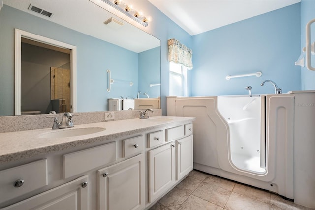 bathroom featuring double vanity, a stall shower, a sink, and visible vents