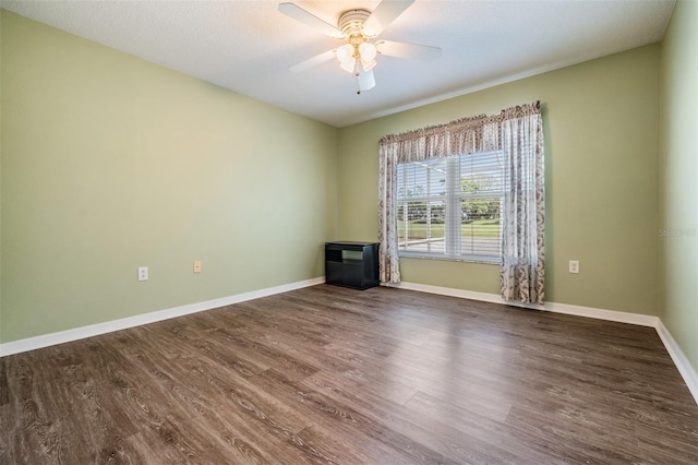 empty room featuring dark wood-style flooring, ceiling fan, and baseboards