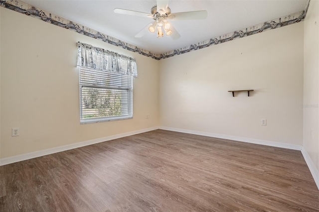 spare room with ceiling fan, wood finished floors, and baseboards