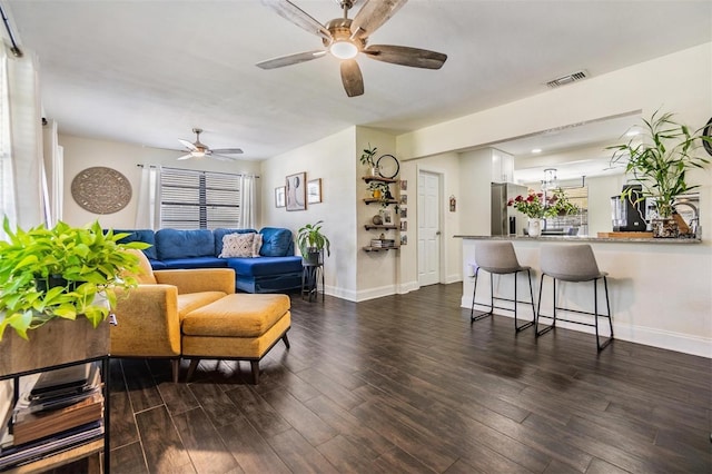 living room featuring dark wood-type flooring, a wealth of natural light, visible vents, and ceiling fan