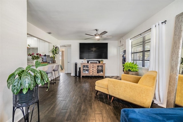 living room featuring dark wood-type flooring, visible vents, ceiling fan, and baseboards