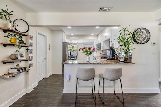 kitchen with visible vents, white cabinets, dark wood finished floors, a peninsula, and light stone countertops