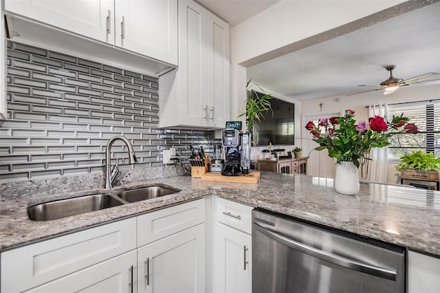 kitchen featuring backsplash, white cabinetry, a sink, light stone countertops, and dishwasher