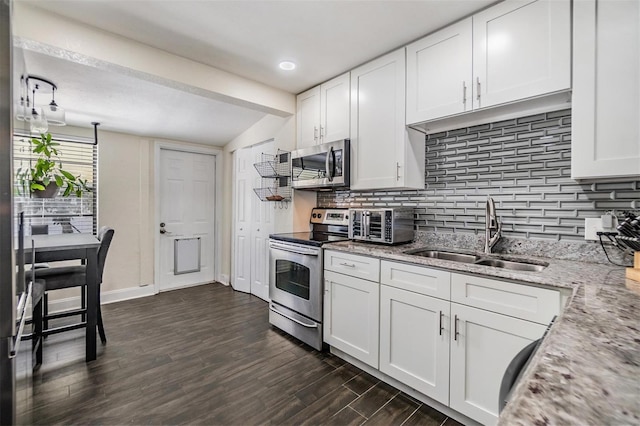 kitchen with decorative backsplash, appliances with stainless steel finishes, light stone counters, white cabinetry, and a sink