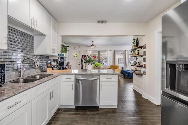 kitchen with appliances with stainless steel finishes, white cabinets, and a peninsula