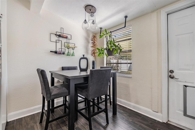 dining area with a textured wall, baseboards, and wood finish floors