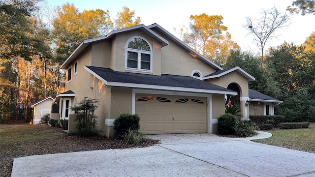 view of front facade with a front yard, concrete driveway, roof with shingles, and stucco siding