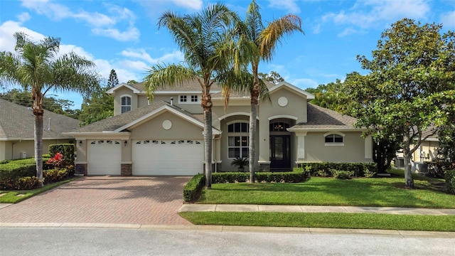 view of front of property featuring a front lawn, decorative driveway, an attached garage, and stucco siding