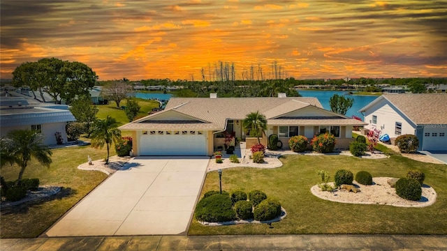 view of front of property with driveway, roof with shingles, a yard, a water view, and a garage