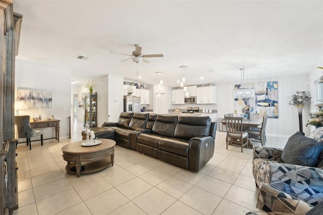 living area with light tile patterned floors, ceiling fan, visible vents, and baseboards