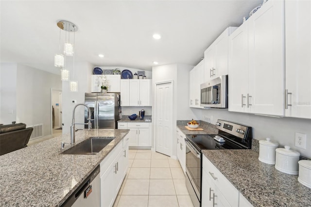 kitchen featuring stainless steel appliances, a sink, white cabinets, hanging light fixtures, and light stone countertops