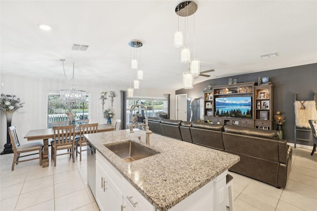 kitchen with a center island with sink, visible vents, white cabinets, and decorative light fixtures