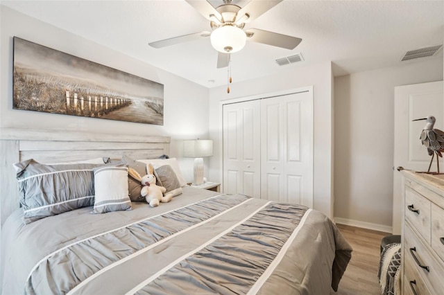 bedroom with a closet, visible vents, light wood-style flooring, and baseboards