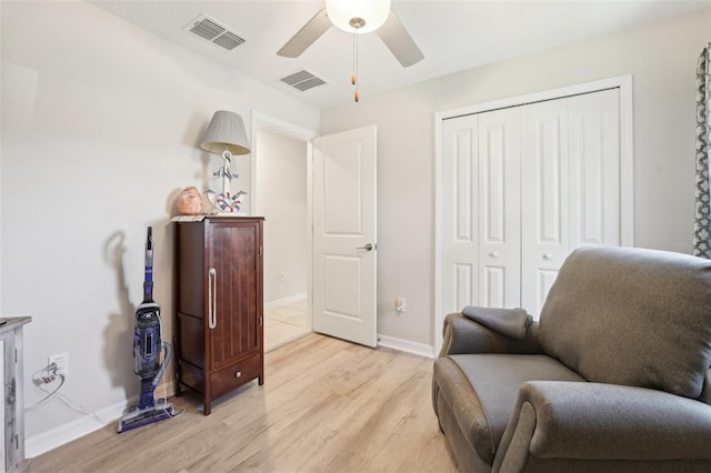 sitting room with baseboards, light wood-type flooring, visible vents, and a ceiling fan