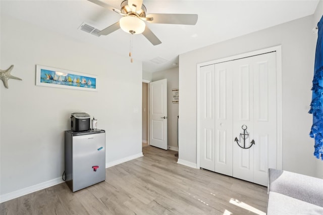 bedroom featuring a ceiling fan, visible vents, baseboards, a closet, and light wood finished floors