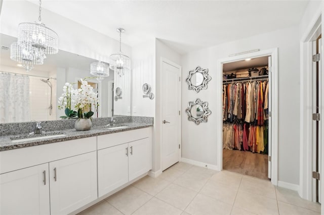 full bath featuring a walk in closet, tile patterned floors, a sink, and double vanity