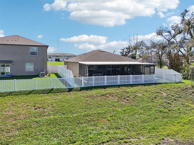 back of property with central air condition unit, a sunroom, a fenced backyard, and a lawn