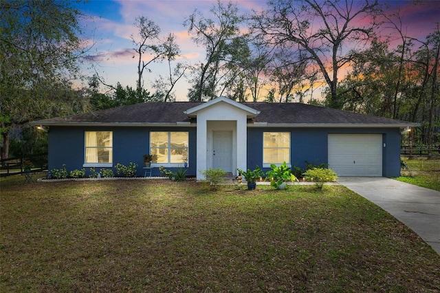 ranch-style house featuring a garage, a yard, and stucco siding