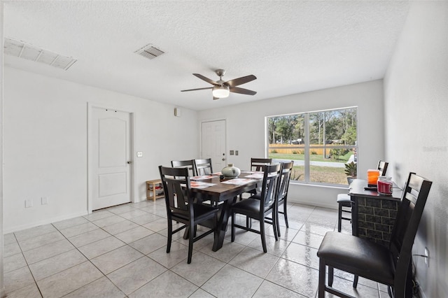 dining space featuring light tile patterned floors, ceiling fan, a textured ceiling, and visible vents