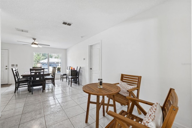 dining space featuring light tile patterned floors, a ceiling fan, visible vents, and a textured ceiling