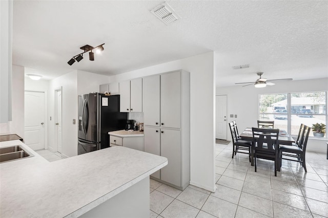 kitchen featuring a textured ceiling, light tile patterned floors, visible vents, light countertops, and black fridge