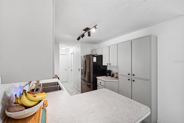 kitchen with light countertops, a sink, and refrigerator with ice dispenser