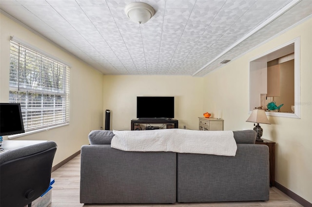 living area featuring baseboards, visible vents, and light wood-style flooring