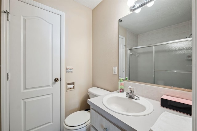 bathroom featuring a shower with shower door, vanity, and toilet