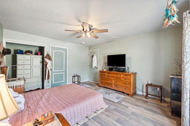 bedroom with visible vents, ceiling fan, a textured ceiling, wood finished floors, and baseboards