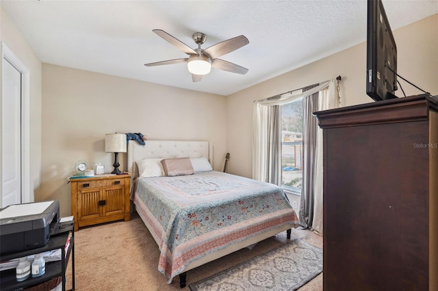 bedroom with light carpet, ceiling fan, and a textured ceiling