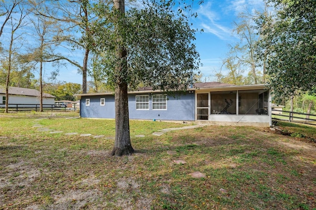 rear view of house with a yard, fence, and a sunroom