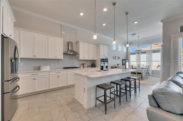 kitchen with stainless steel appliances, backsplash, open floor plan, white cabinets, and wall chimney exhaust hood