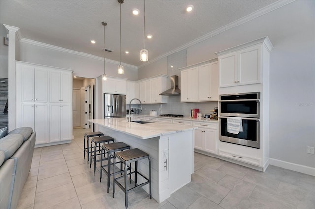 kitchen featuring a breakfast bar, a sink, wall chimney range hood, appliances with stainless steel finishes, and tasteful backsplash