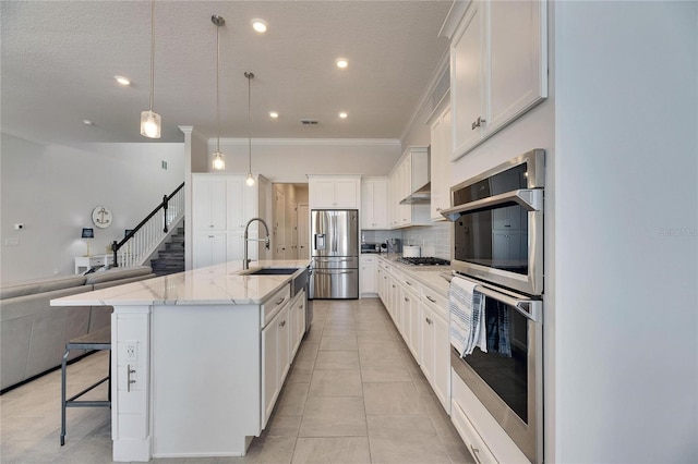 kitchen featuring appliances with stainless steel finishes, a breakfast bar, open floor plan, white cabinetry, and a sink