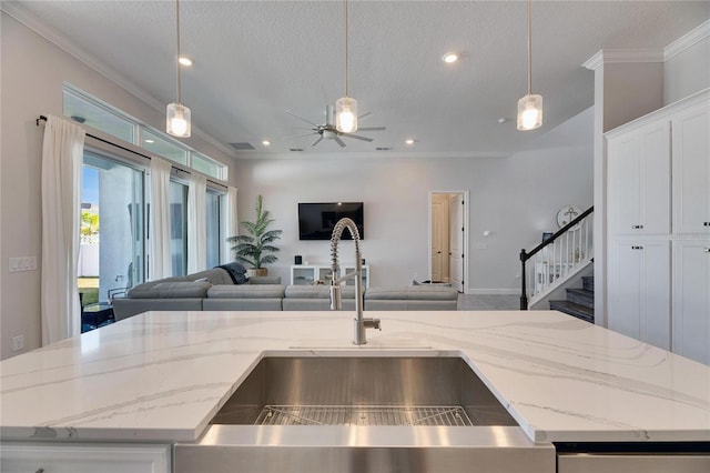 kitchen featuring open floor plan, ornamental molding, and a sink