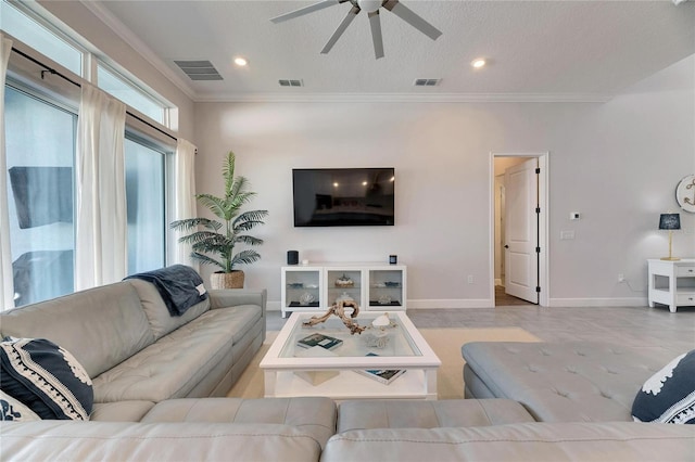 living room with ornamental molding, visible vents, and baseboards